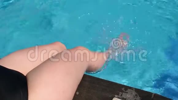 年轻女子在游泳池里玩得很开心她坐在池边溅起水花视频的预览图