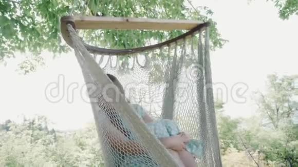 漂亮的女人坐在树影的吊床上睡觉舒适的休闲场所视频的预览图