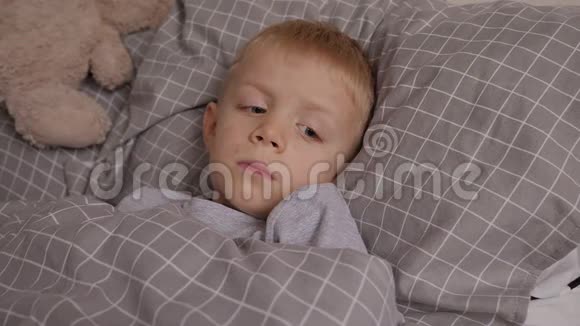 一张躺在床上的小男孩的肖像他的皮肤上有水痘引起的红疹视频的预览图