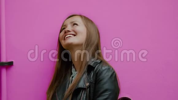 年轻幸福的女人的彩色肖像微笑着仰望粉红色的墙视频的预览图