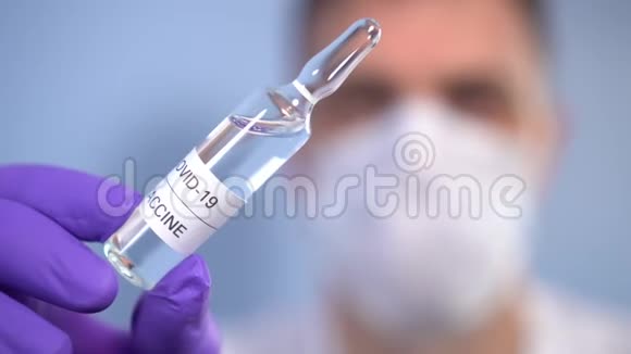 冠状病毒疫苗一位戴着防护手套和面罩的生物学家手里拿着一个安瓿里面有一种COVID19的药视频的预览图