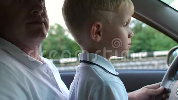 特写小男孩坐在他父亲的手上的车轮在车里视频的预览图