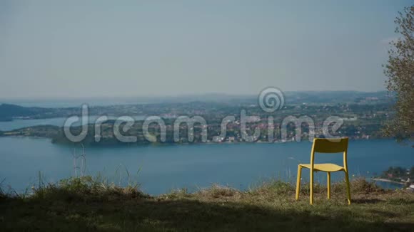 穿着帽子的女孩坐在椅子上坐下来欣赏蓝色的湖景视频的预览图