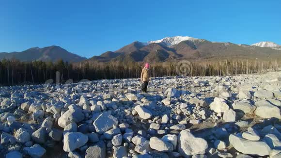 一个女孩走过一块到处是大石头的田野慢动作视频的预览图