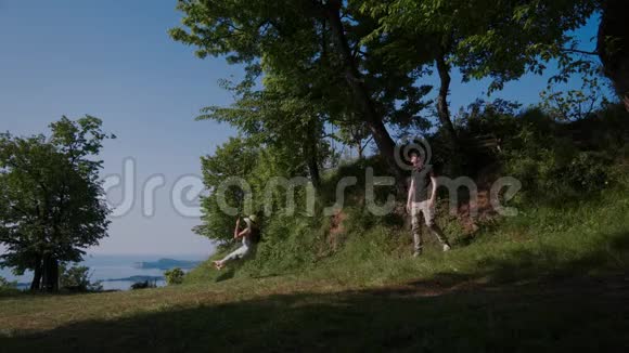 男人在自然景观中摇摆着女孩草帽飞到女孩子头上视频的预览图