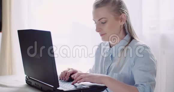 微笑的女人在家里的办公室用笔记本电脑工作女商人在电脑键盘上打字视频的预览图
