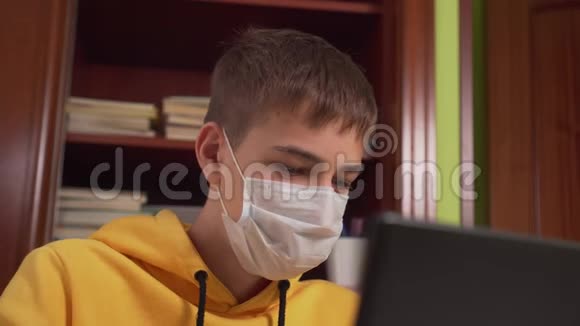 青少年在家里笔记本电脑前戴面膜的远程学习视频的预览图