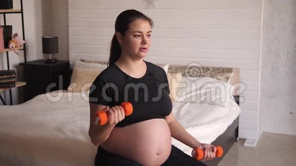 孕妇在床上坐在家里做哑铃运动视频的预览图