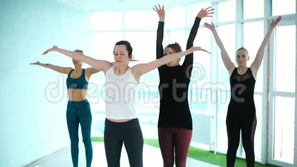 教练教年轻女子体式瑜伽在一个灯光工作室视频的预览图