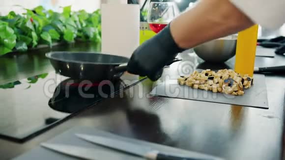 厨师用现代设备在厨房用炒锅炒菜时用手套把他的手合起来视频的预览图