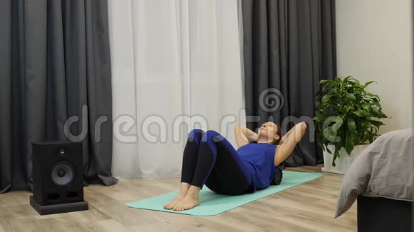 女孩在客厅做运动女性按摩脊柱肌肉使用滚筒瑜伽健身教练做复健运动视频的预览图