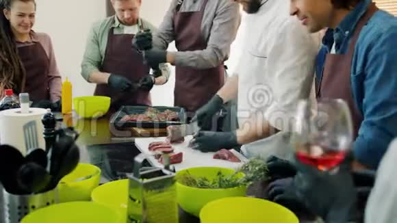 在烹饪过程中不同的快乐人群穿着围裙在厨房做饭视频的预览图