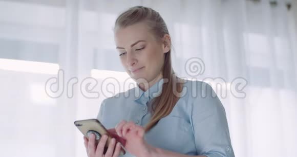 快乐的女人在家里浏览智能手机视频的预览图