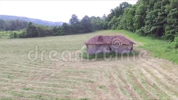 在草地中央的老房子和废弃的小屋上空飞行视频的预览图