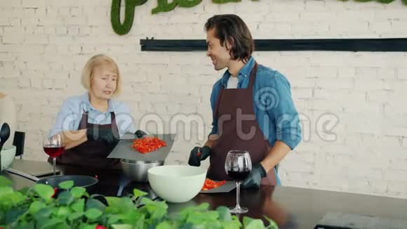 女人和男人穿着围裙在厨房做饭在烹饪大师级的时候交谈视频的预览图