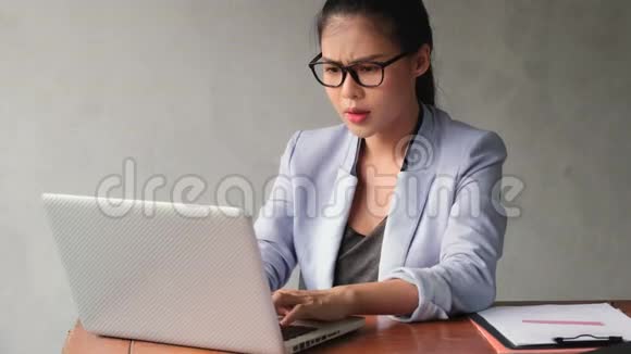 年轻的亚洲妇女在办公室里用笔记本电脑工作对她的工作感到压力视频的预览图
