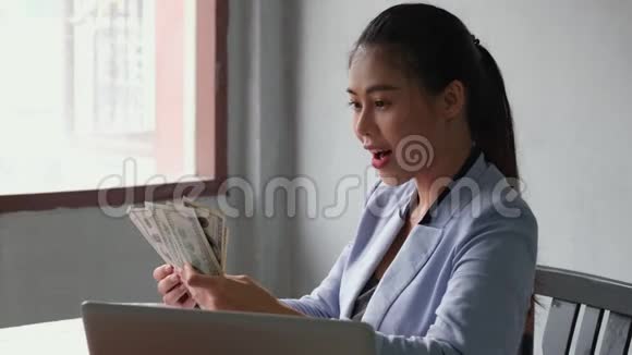 美丽的亚洲女人拿着钞票亲吻它在数钱的过程中感到非常快乐和微笑视频的预览图