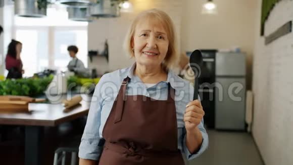 穿围裙的老太太在烹饪课上微笑享受教育的肖像视频的预览图