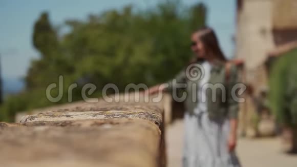 戴墨镜的女孩牵着他的手沿着中世纪意大利堡垒的石墙走视频的预览图