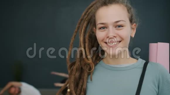 美丽的年轻女子戴着可怕的锁在健身房里拿着瑜伽垫微笑视频的预览图