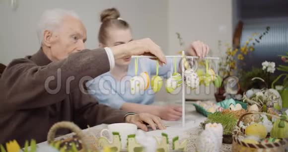 老人和孙女装饰桌与复活节彩蛋和复活节装饰视频的预览图