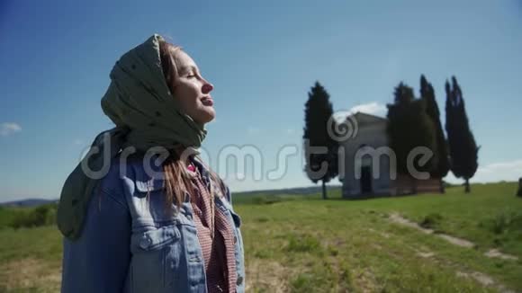 戴头巾的漂亮女人在教堂和女裙的背景下享受阳光视频的预览图