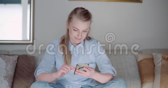 快乐的女人在家里浏览智能手机视频的预览图