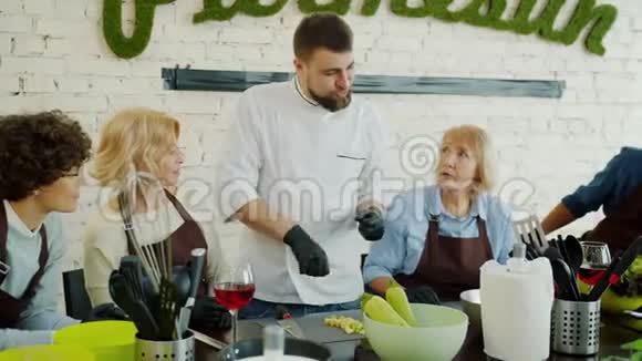 男厨师穿着制服在烹饪课上和一群人交谈讨论食物视频的预览图