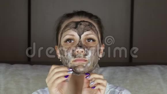 美丽的女人从脸上摘下清洁的黑色面具视频的预览图