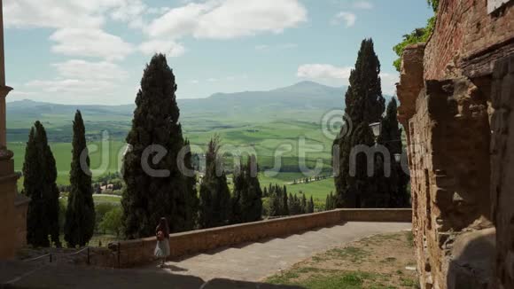 穿裙子的女孩走在堡垒的石阶上俯瞰美丽的风景视频的预览图