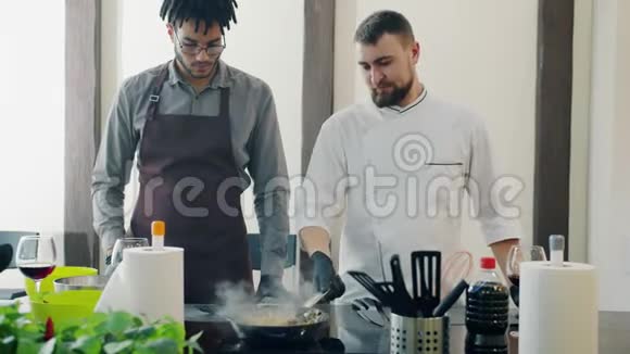 男厨师教师非裔美国人受训人员用平底锅在厨房里煎食物视频的预览图