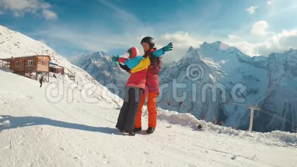 母亲和女儿享受旅程在滑雪场穿着冬装的幸福家庭冬天的时候看着视频的预览图