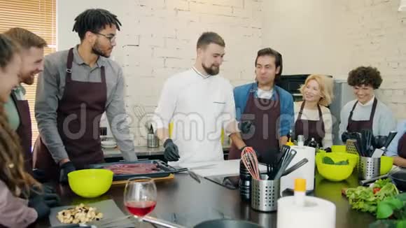 不同的人群穿着围裙在厨房烹饪课程中烹饪食物视频的预览图