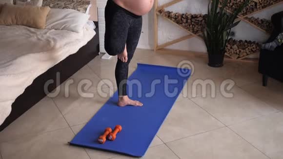 年轻孕妇在家里在蓝色垫子上做健身和瑜伽练习视频的预览图