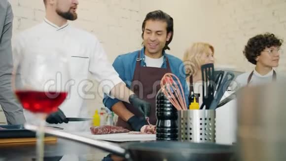 女孩和男人在学习烹饪看厨师在现代厨房准备菜肴视频的预览图