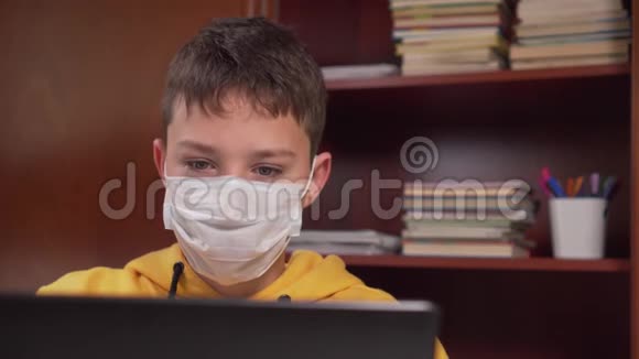 青少年在家在线学习带着笔记本电脑戴着面膜在一个有衣柜的房间里视频的预览图