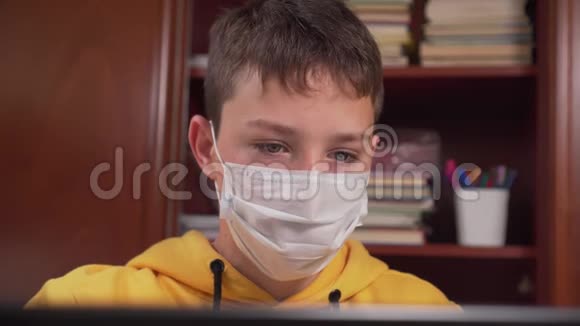 戴着防护面罩的青少年在笔记本电脑前在线学习同时隔离冠状病毒视频的预览图