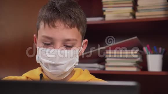 十几岁的孩子在家里用笔记本电脑上网戴着防护面罩背景是一个木制的的防护面罩视频的预览图
