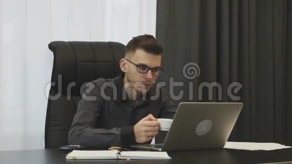 男人在他现代的办公室里喝咖啡穿西装戴眼镜的年轻商人在工作场所喝咖啡男性金融家视频的预览图