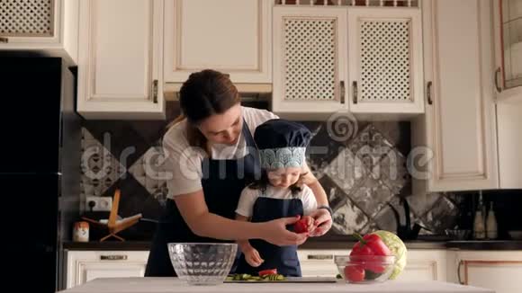 妈妈带着女儿在厨房里玩女孩拿着新鲜的西红柿视频的预览图