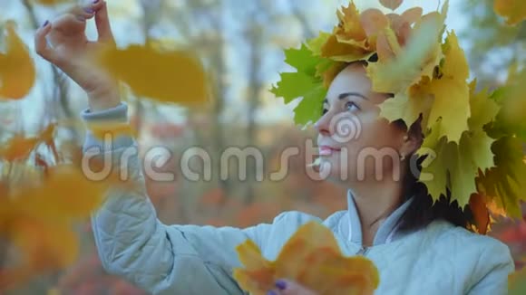 头上戴着秋叶花环的美女在检查被撕碎的叶子视频的预览图