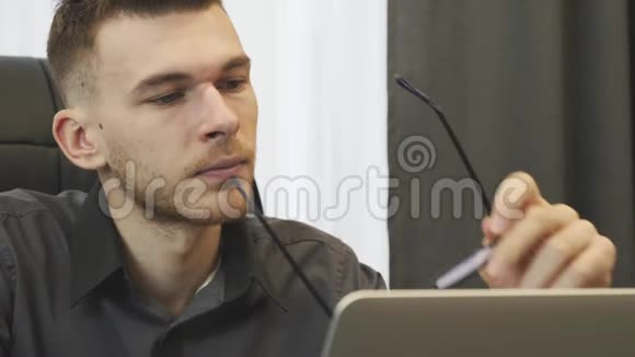 商人在网上看新闻特写男人的肖像戴上眼镜看着笔记本电脑屏幕男职工视频的预览图