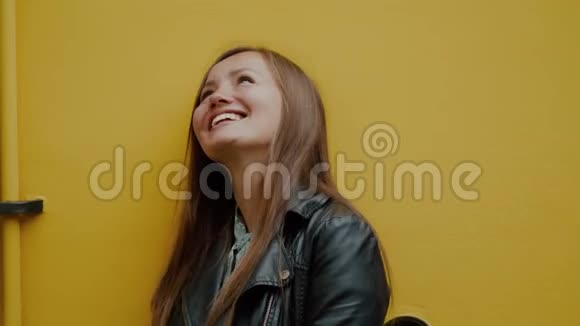 年轻幸福的女人在黄色的墙上微笑着仰起头的彩色肖像视频的预览图