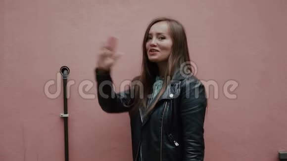 年轻积极可爱深褐色的女孩在浅粉色的墙壁上亲吻空气视频的预览图