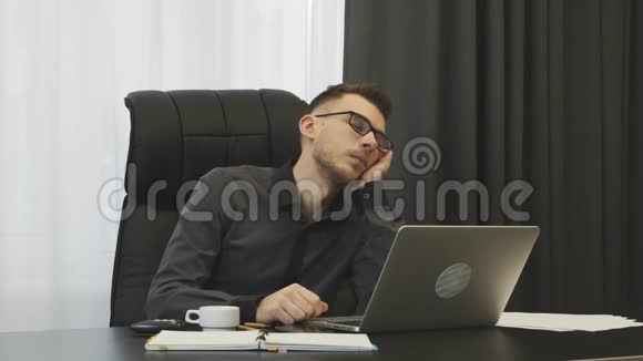 疲倦的人睡在工作场所的办公室里男员工几乎从办公桌上掉下来商人工作过度劳累视频的预览图