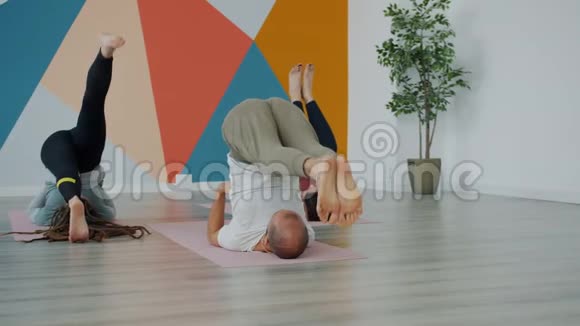 一组瑜伽学生在练习倒姿势时把腿抬高躺在垫子上视频的预览图