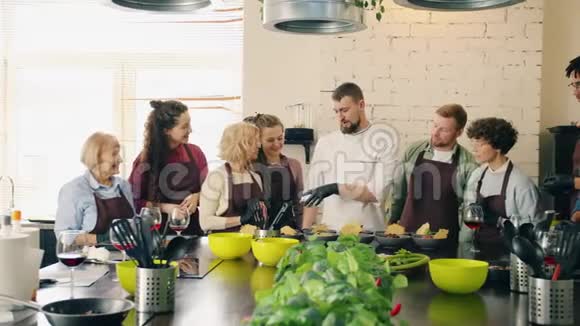 一群男人和女孩拍手给厨师在厨房里拿着熟食视频的预览图