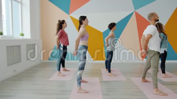 年轻男女在瑜伽室弯腰练习的慢动作视频的预览图