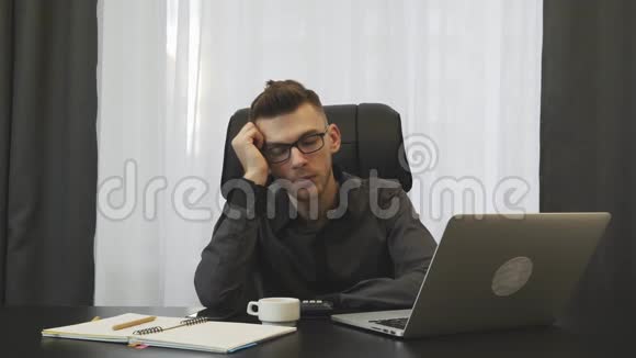 男性顾问在工作场所睡觉穿西装戴眼镜的年轻人睡在现代办公室里商人工作累了青年视频的预览图