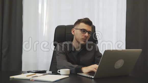 在现代办公室里操作笔记本电脑的人那个商人在办公室里用电脑加班累了男性独自在笔记本电脑上工作视频的预览图
